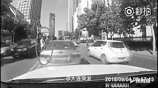 两人路中央握手寒暄,旁边车道上驶过十多辆车。