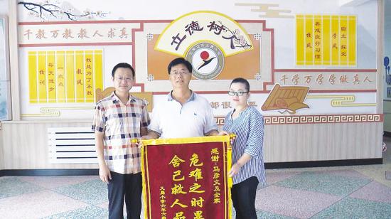 为表谢意,学校负责人及孩子家长将一幅锦旗送到了马彦文(中)手中。