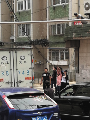 女老师主动拽着网线,让过往车辆通行