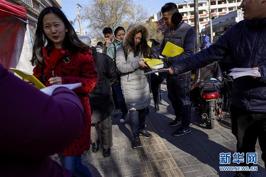 12月10日，上午考试结束后，考生走出北京一考场，各类考试辅导机构的工作人员向考生发放辅导材料。 2018年“国考”共有165.97万人通过了用人单位的资格审查，较去年增加了17.34万，通过资格审查人数与录用计划数之比为58：1。新华社记者沈伯韩摄