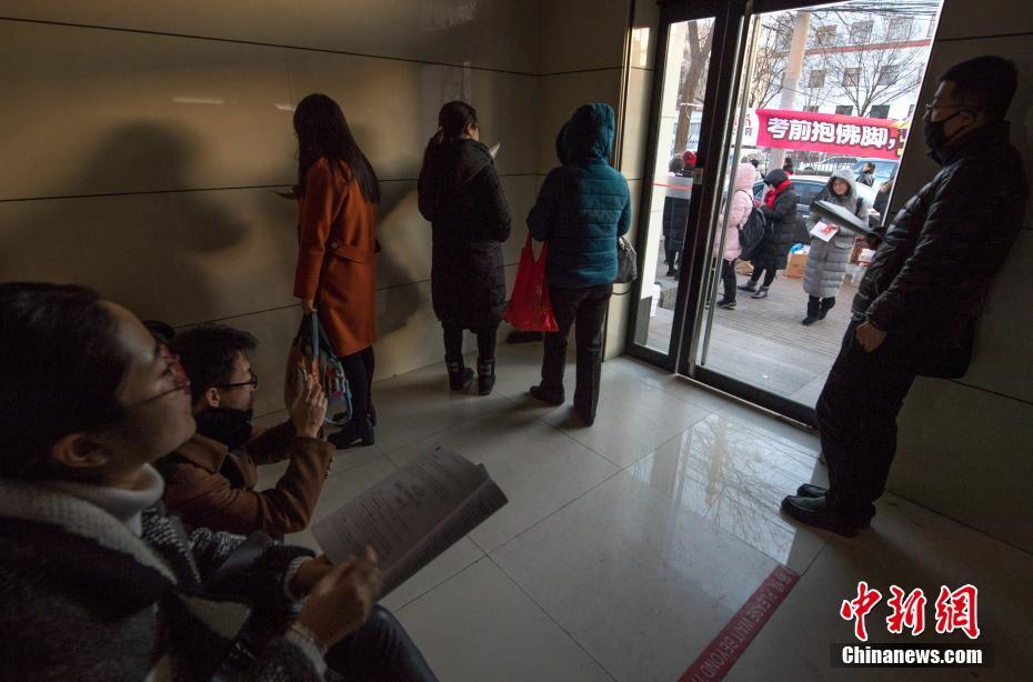 12月10日，考生在一公务员考点外的自助银行内抓紧时间复习。当日，2018年度中央机关及其直属机构公务员招考笔试开考。本次国考计划招录2.8万余人，最终有165.97万人通过报名资格审查，较去年增加了17.34万，通过资格审查人数与录用计划数之比为58：1。 中新社记者 武俊杰 摄