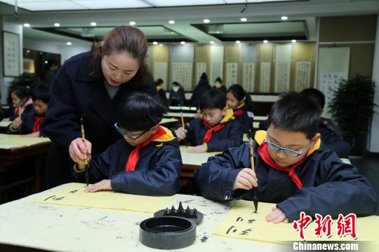 同学们在老师的指导下练习书法。　郑逸洁 摄