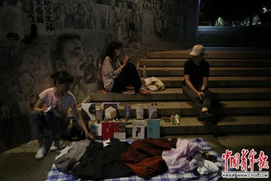 6月19日晚，中央美术学院，硕士毕业生钟钰炜（左一）与朋友在跳蚤市场上摆摊，身后的壁画描绘了央美百年历史。中国青年报·中国青年网见习记者 孔斯琪/摄
