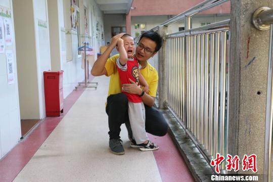  杨建琪耐心安抚一名哭闹的孩子。　林馨 摄