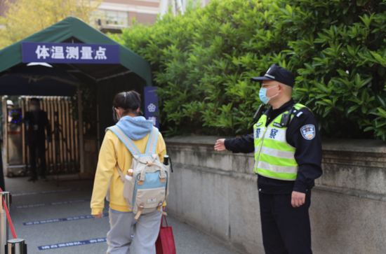 浦东公安分局民警在校门口引导学生开展体温检测。上海市公安局供图