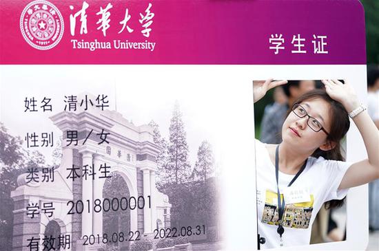 8月22日，在清华大学综合体育馆外，一名新生与“学生证”特色海报合影留念。