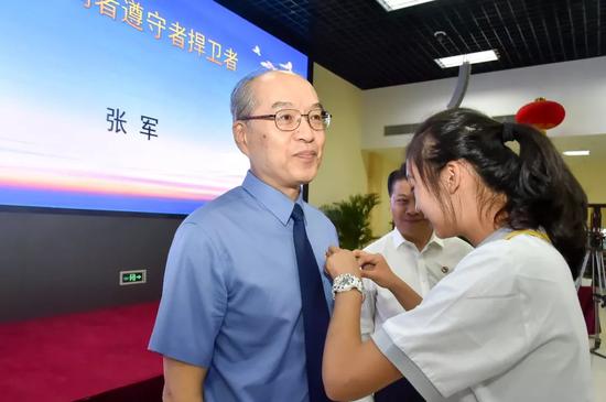 学生代表为张军检察长佩戴北京市第二中学校徽。