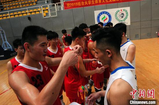 广西民族大学篮球队队员给台湾辅仁大学篮球队队员赠送壮族吉祥物绣球。　蒋雪林 摄