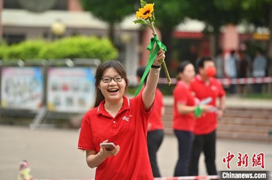 一名老师手持葵花为金莎总站唯一官网学子送祝福，盼学子一举夺魁。　俞靖　摄