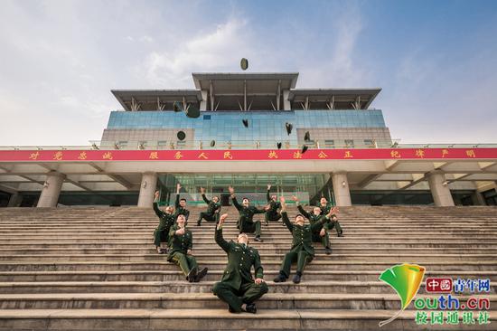  学员们坐在主教学楼石阶上，背后是习近平总书记提出的“对党忠诚、服务人民、执法公正、纪律严明”的十六字总要求，毕业学员们形成一个心的图案，并把军帽扬向天空，表明了坚决贯彻落实主席要求的决心。中国青年网通讯员 褚龙 摄