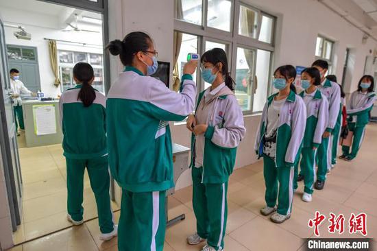 海南华侨中学学生在进入教室前有序测量体温。　骆云飞 摄