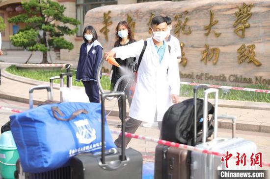 在广州市黄埔区华南师范大学附属初级中学，工作人员正给学生的行李消毒。　钟飞兴　摄