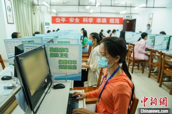 资料图：7月16日，广西壮族自治区招生考试院举办高考评卷开放日活动。图为教师佩戴口罩隔座阅卷。　陈冠言 摄