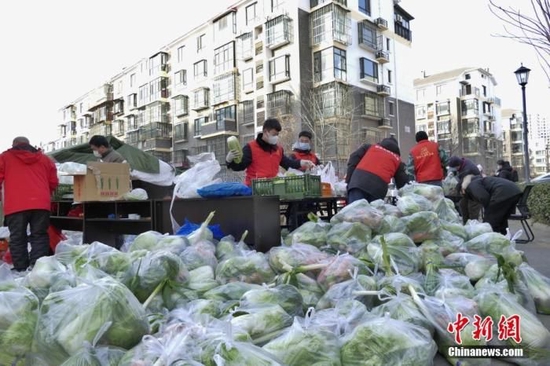 资料图:社区工作者在生活物资保障点为居民分装蔬菜。中新社记者 佟郁 摄