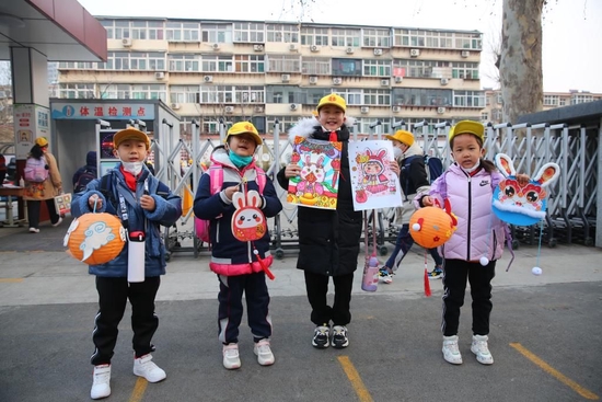 2月6日,开学首日,山东省济南市经十一路小学的部分学生,在校门口展示自己的兔年文创作品。(受访单位供图)