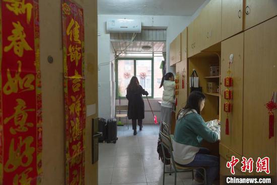 记者见到来自河北石家庄的魏子璇与潘红丽时,她们正在贴窗花,寝室内的柜子也挂上了小小的红灯笼,门口也贴上了春联,年味十足。 刘力鑫 摄
