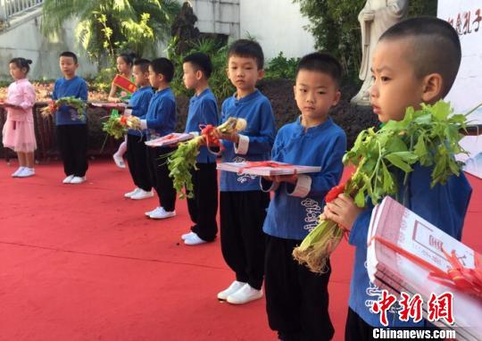 图为老师向学生送葱、芹菜及国学读物，寓意聪明与勤奋。　张立庆 摄