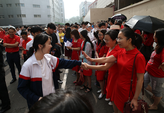 6月7日，北京陈经纶中学高考考点，身着红色衣服的老师与即将进入考场的考生们拉手鼓劲。当日，2019年全国高考正式拉开大幕，超千万考生奔赴考场。