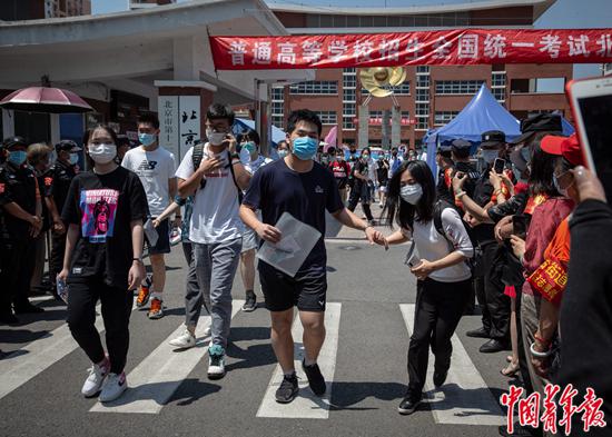 2020年7月7日上午,北京市丰台区,北京市第十二中学考点,结束上午的考试后,高考考生们走出考场,一名考生从人群中牵起家人的手。 中青报·中青网记者 李峥苨/摄