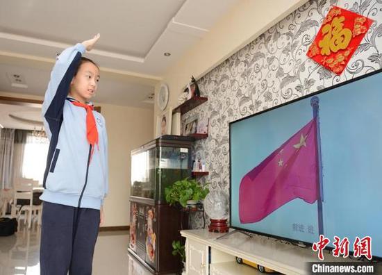 2月29日，小学4年级学生王佳琪在家中，通过视频参加线上升旗仪式。　刘文华 摄