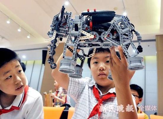 图说:小学生举起自己创意制作的机器“猛犸象”