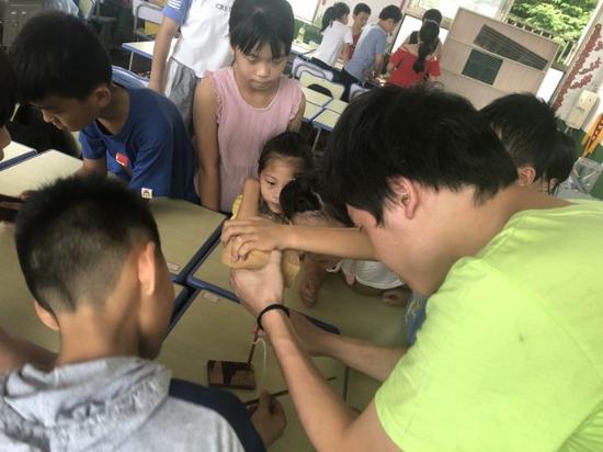 志愿者和小朋友们一起进行钻木取火的实验
