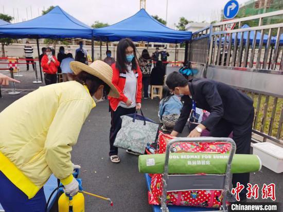 6日下午，北师大海口附属学校学生返校，工作人员对其行李进行消毒。　张茜翼　摄