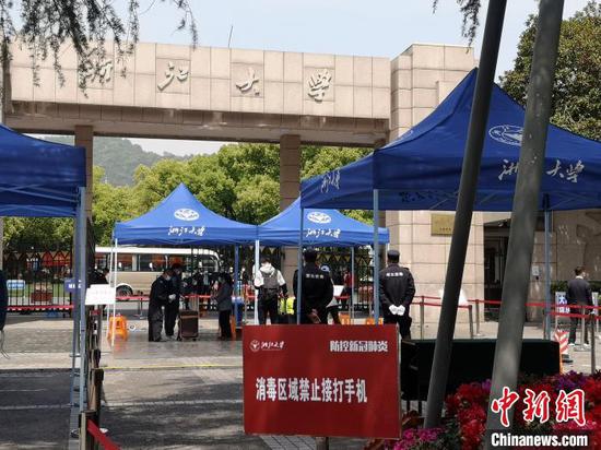 校门口,工作人员对行李箱进行消毒。 童笑雨 摄