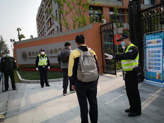 杨浦公安分局新江湾城派出所巡逻队副队长燕巍巍在校门口提醒入校学生保持一米距离。上海市公安局供图