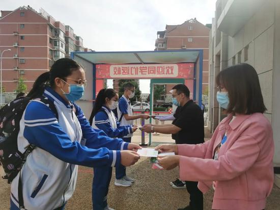 返校进行时,老师们站在校门口热情地欢迎着每一位同学。