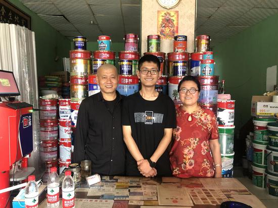 李世华和爸爸妈妈在自家经营的墙面涂料店铺里合照。新京报记者 杜雯雯摄