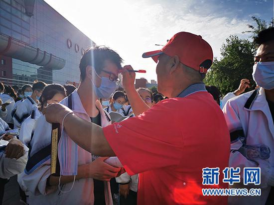宁夏六盘山高级中学高三语文老师崔满仁在学生额前点上象征幸运的红点。