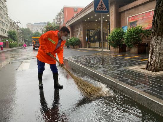 今天上午，北京排水集团工作人员对道路积水进行清理。北京排水集团供图