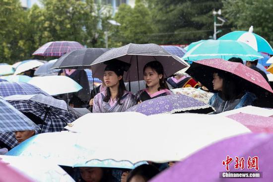 贵州民大2017届毕业生撑着雨伞参加毕业典礼。