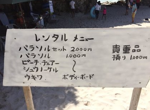 　　图为面向日本人的广告牌(太阳伞套餐组合两千日元，单租太阳伞、沙滩椅之类的一千日元，保管贵重物品一千日元)