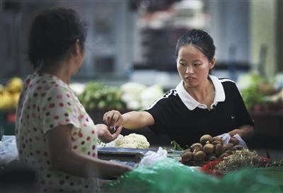 9月8日下午5时，赵金凤在菜市场买蔬菜。母亲平时只能吃素食。图片来源：新京报