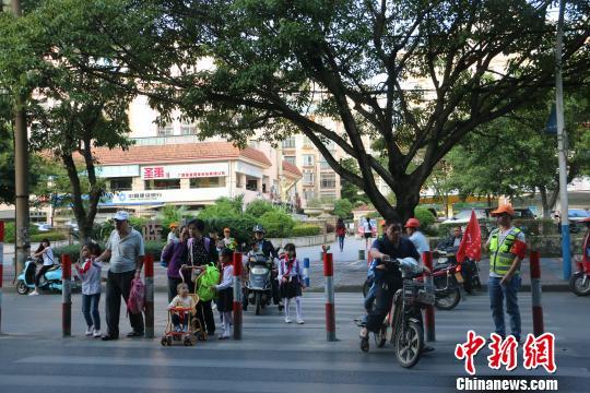 图为学生在家长指引下，有序穿过马路 林馨 摄