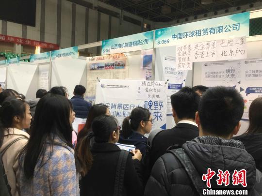 图为招聘展位前，“北京户口”等软福利吸引学生驻足。　项飞 摄