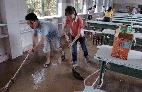 2006年，强降雨导致福建建瓯城区被淹，导致四千多名学生无法参加高考，图为学生打扫被淹的学校食堂。资料片
