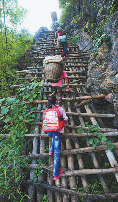 在弄勇村弄顶屯，孩子们扛着生活用具，爬悬梯回家（2012年7月4日摄）。