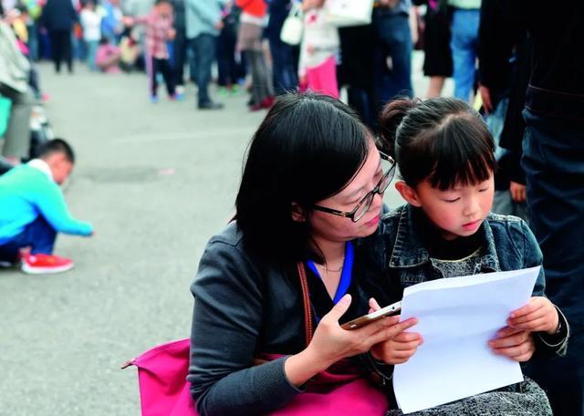 　　（（资料图片）一名参加上海市七宝外国语小学（民办小学）招生面谈的孩子和妈妈一起阅读面谈注意事项。图/新华）