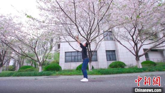 屠锋锋在校园樱花树下跳舞，为学生带来“云端”舞蹈鉴赏。校方提供