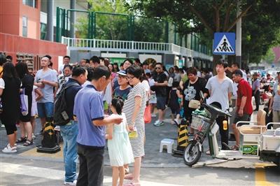 2017年6月17日，北京，又到了每年一度的“幼升小”报名时间，家长一早便领着孩子，顶着高温到学校门口排队。图/视觉中国