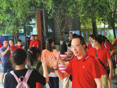  7月6日，成都七中万达学校刘强校长与考生们击掌加油鼓劲。