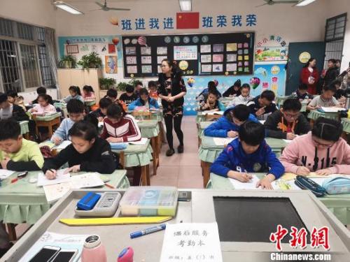 学生正在写作业，一名教师在值班。　朱柳融 摄
