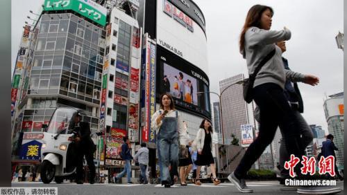 资料图片：2017年5月17日，日本东京新宿商业区，人们穿过街道。