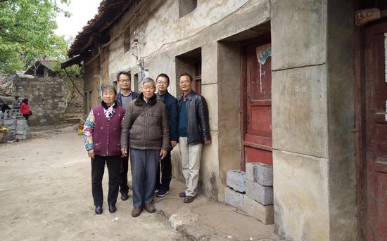 袁明磊兄弟三人和父母亲在家乡老宅前合影留念。受访者供图