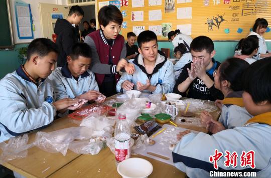 2018年3月2日是中国传统节日--元宵佳节,兰州市城关区华侨实验学校开展了“华彩新春,闹元宵猜灯谜”灯展主题活动。图为包汤圆。(资料图) 刘玉桃 摄