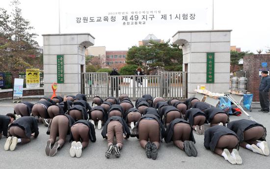 韩国一高中前，后辈为参加高考的前辈行大礼。（韩联社）