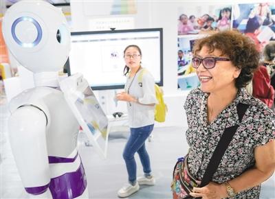 在首届中国北京国际语言文化博览会上，一名参观者与智能客服机器人交流。